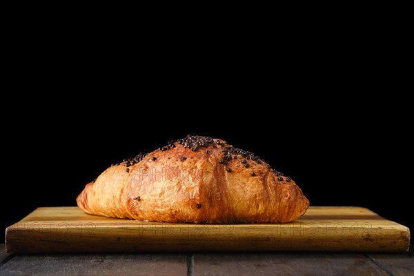 Croissant with chockolate icing on wooden serving board
