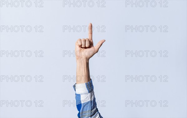 Hand gesturing the letter L in sign language on an isolated background. Man's hand gesturing the letter L of the alphabet isolated. Letters of the alphabet in sign language