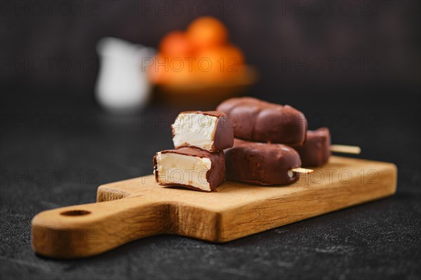 Homemade curd bars in chocolate on wooden board