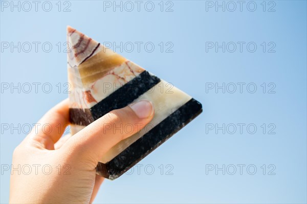 Hand holding a pyramid made of marble in air