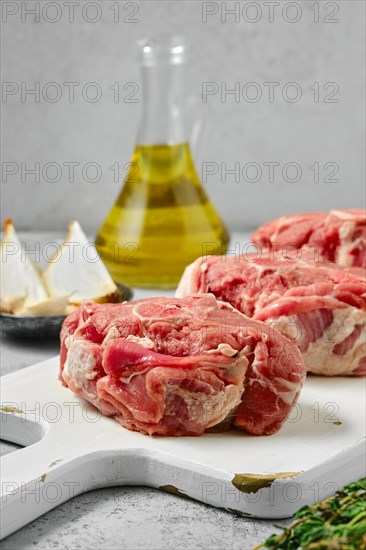 Uncooked raw lamb loin chops saddle steaks on wooden cutting board