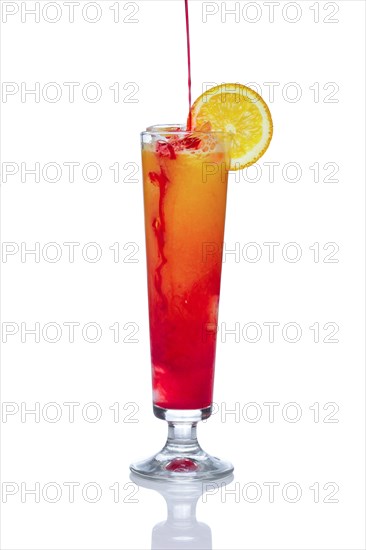 Orange alcohol cocktail with strawberry. Pouring berry liqueur. Isolated on white background