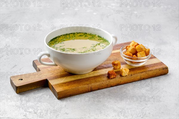 Chicken stock with croutons on wooden serving board