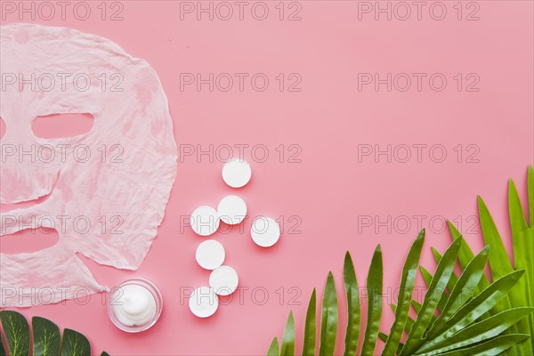 Paper sheet face mask moisturizer green leaves pink background