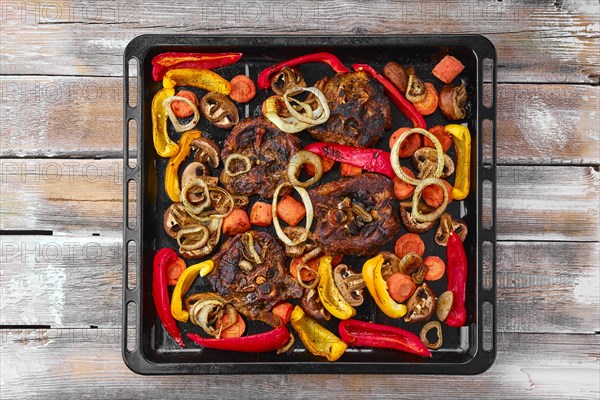 Lamb neck with champignon and vegetables baked in oven on wooden table