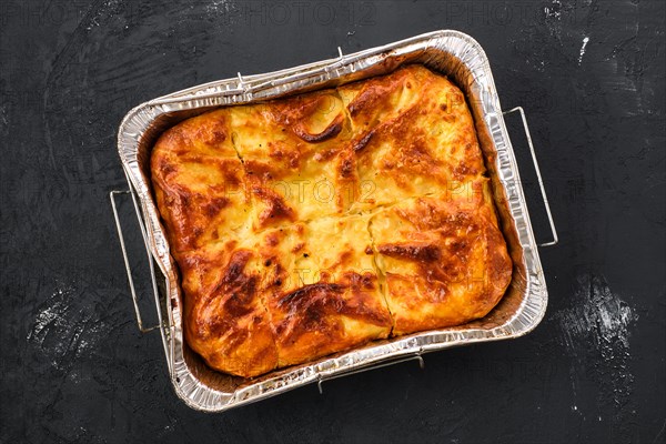 Georgian pie with cheese achma on black wooden background