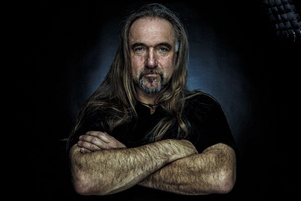 Man with long hair and hand with folded arms