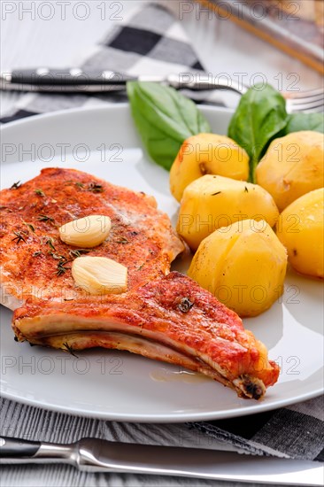 Steak with bone and potato baked in oven in a roasting pan with garlic and thyme
