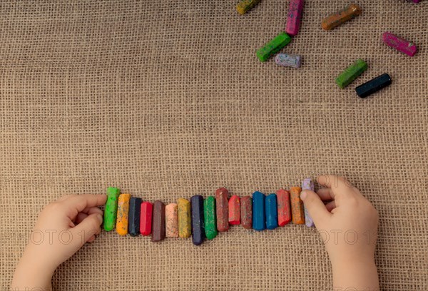 Toddlers hand putting crayons in line on canvas