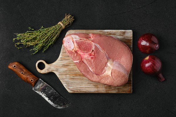 Overhead view of raw slice of beef steamship round with cooking ingredients on black background