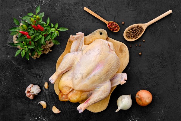 Fresh raw whole farm chicken on wooden cutting board