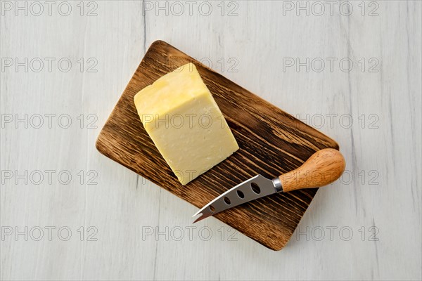 Top view of triangular piece of hard cheese on wooden cutting board