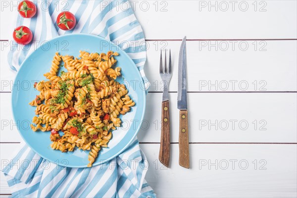 Pasta fusilli with tomato cutlery white wooden table