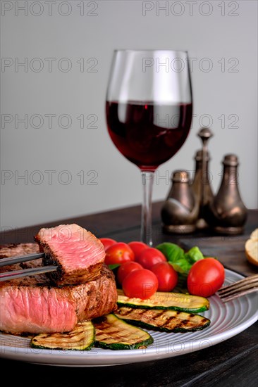 Grilled beef steak and zucchini served with fresh tomato cherry and basil and a glass of red wine
