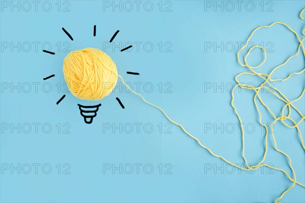 Illuminated yarn yellow light bulb blue background