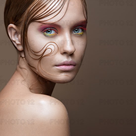 Beautiful girl with bright colored makeup and wet strands of hair on the face. Creative image. Picture taken in the studio