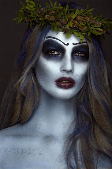 Portrait of a horrible scary Corpse Bride in wreath with dead flowers