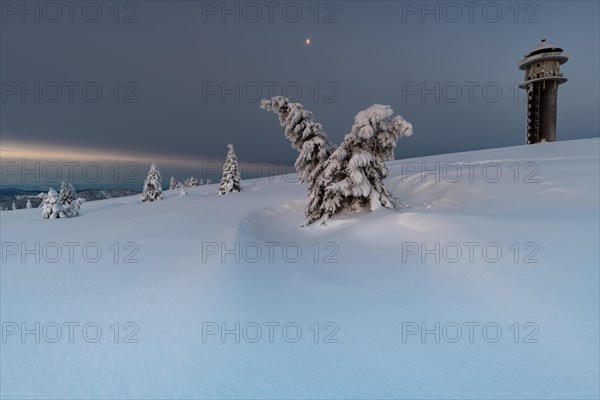 Snow-covered trees and landscape and the new Feldberg tower on the Feldberg in front of sunrise