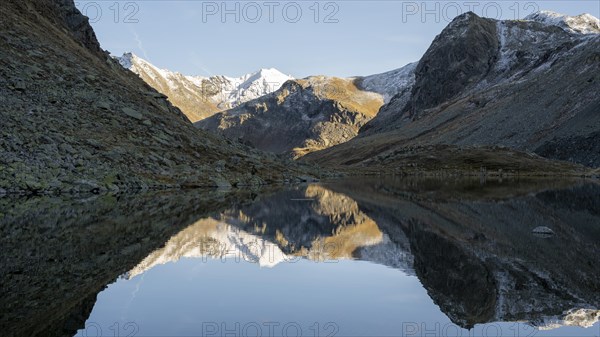 Slightly snow-covered mountains reflected in Schwarzsee in autumn on the Flueela Pass