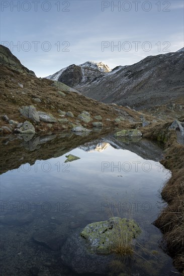 Lightly snow-covered mountains and mountain lake in autumn on the Flueela Pass