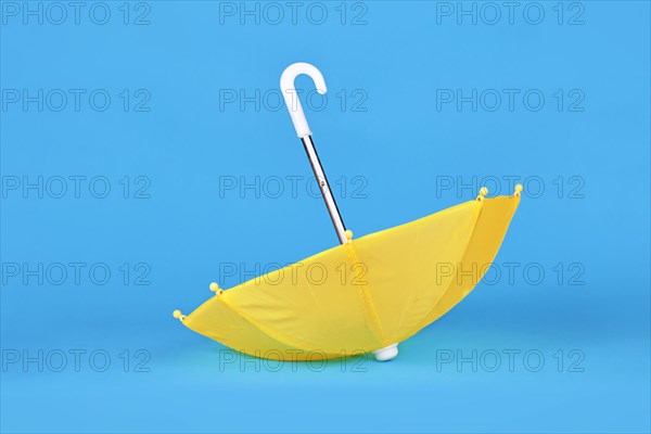 Yellow doll umbrella upside down on blue background