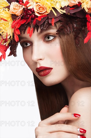 Beautiful girl with bright autumn wreath of leaves and flowers. Beauty face. Picture taken in the studio on a white background