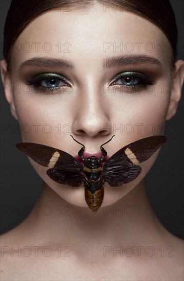 Portrait of beautiful girl with colorful make-up and cicada. Beauty face. Photo taken in the studio