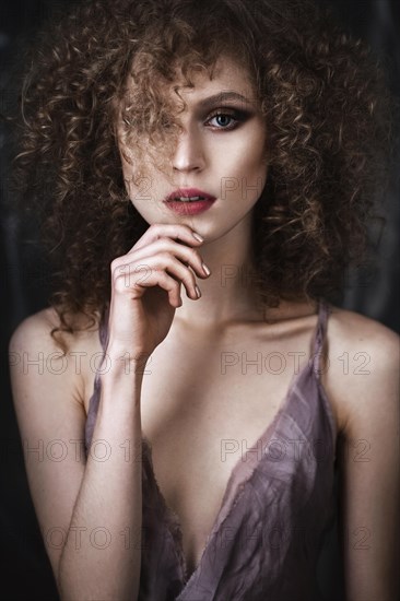 Beautiful girl with curly hair in lingerie with large flower. The beauty of the face. Photos shot in studio
