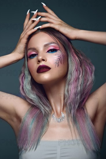 Beautiful girl with multi-colored hair and creative make up and hairstyle. Beauty face. Photo taken in the studio