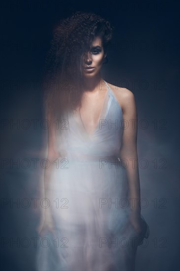 Beautiful girl in a light blue dress and long hair in a fashionable image. Beauty fashion style. Picture taken in the studio with mixed light