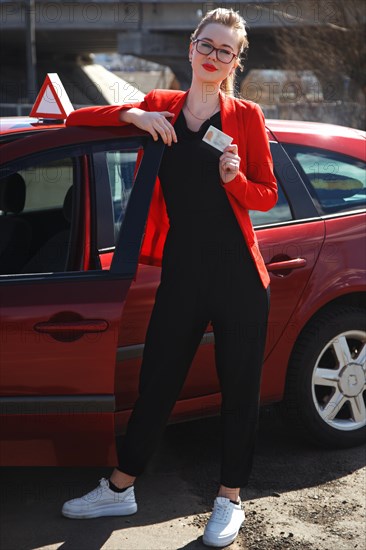 Joyful girl driving a training car with a drivers license card in her hands