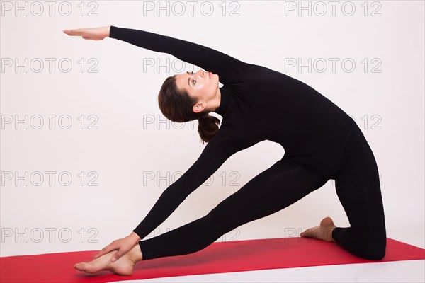 Beautiful athletic girl in black suit doing yoga asanas. Isolated on white background