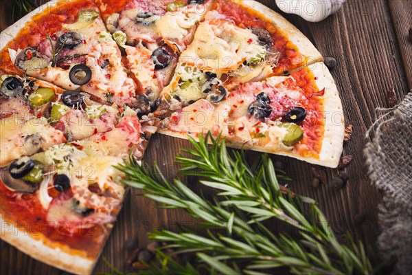 Sliced tasty fresh pizza with mushrooms and sausage on a wooden background. View from above. Close-up