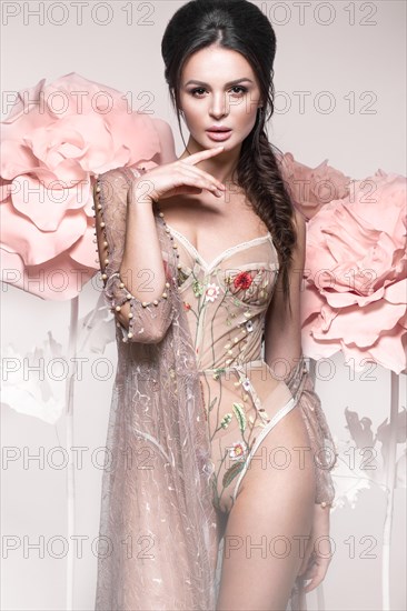 Beautiful girl with classic make-up and hairstyle in delicate Underwear with large flowers on background. beauty face. Photos shot in studio
