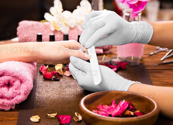 Closeup finger nail care by manicure specialist in beauty salon. Manicurist clear cuticle professional nail file for manicure and pedicure