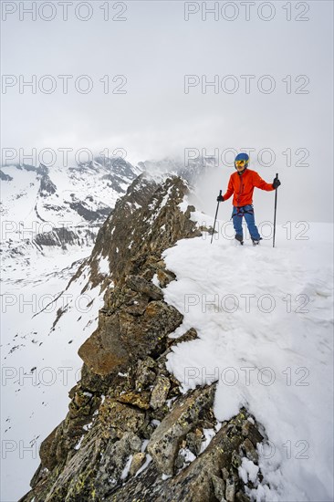 Ski tourers on rocky ridge with snow