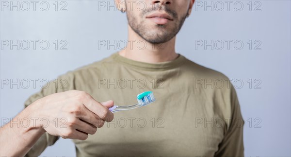 Guy with unrecognizable face holds brush with toothpaste on isolated background