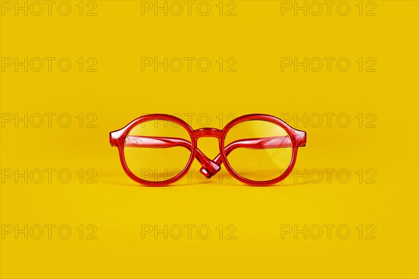 Small red round eye glasses on yellow background