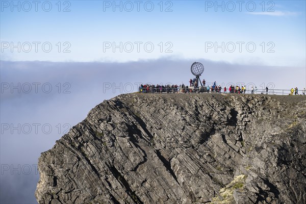 Rock cliff of the North Cape with steel globe at midnight sun