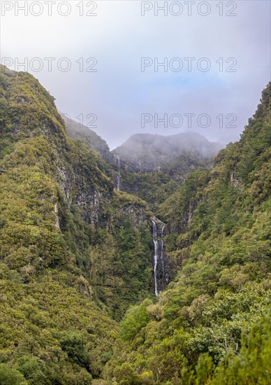 Cascata do Risco waterfall between densely forested mountains