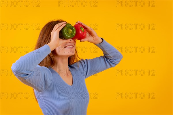Vegetarian woman with spyglasses of peppers on her eyes on a yellow background