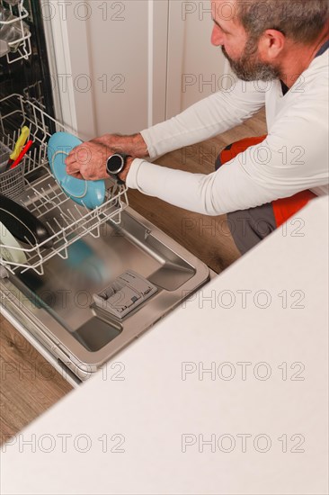 Man in white t-shirt putting the dishes in the dishwasher