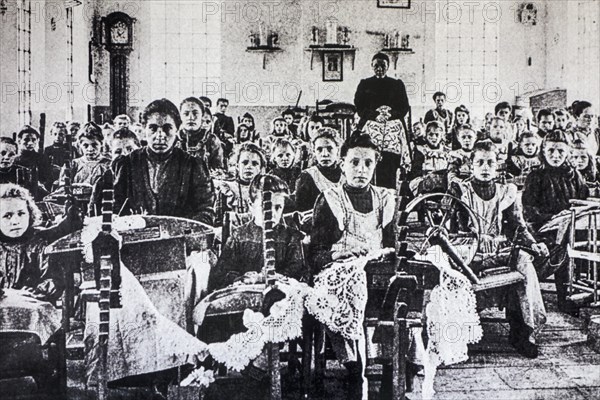 Old archival picture of school children posing in lacemaking class in early twentieth Flanders