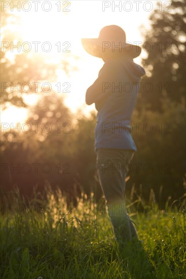 Young woman with hat relaxing in summer sunset sky outdoor