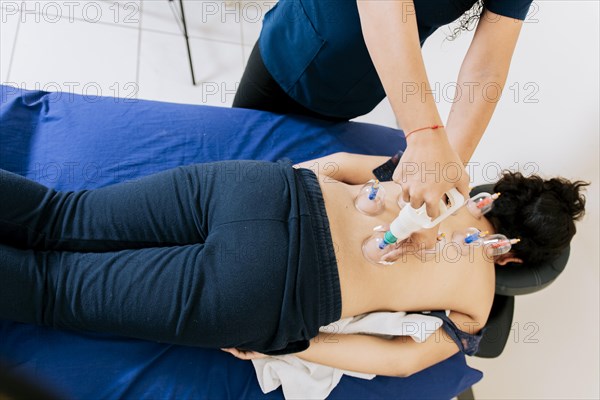 Physiotherapist placing cupping on lying female patient