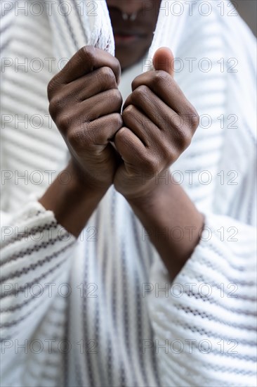 A young man of African ethnicity in a white contemporary suit and black leather boots