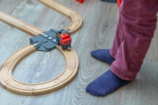 Unrecognizable child playing with his wooden train in his room