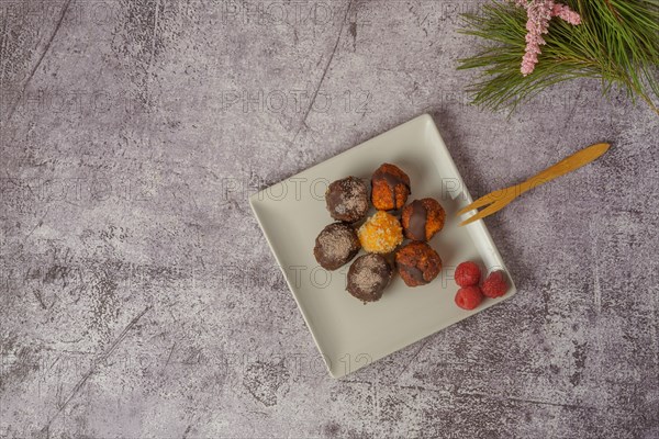 Sweet truffles of different flavors on a white ceramic plate