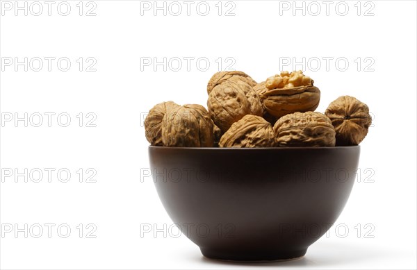 Walnuts in a brown bowl isolated on a white background