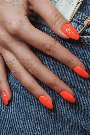 Bright neon manicure on female hands on the background of jeans. Nail design. Beauty hands